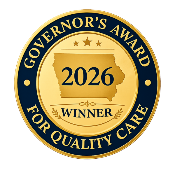 Gold and navy circular badge with the text "Governor's Award for Quality Care," a map of Iowa with "2026" in the center, three stars above the map, and the word "Winner" below, all on a gold background.